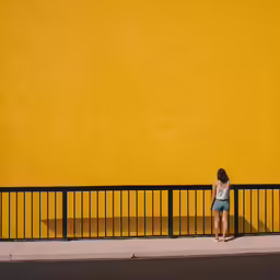 there is a woman standing next to a yellow wall