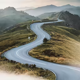 a winding road is shown with mountains in the distance