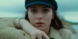 a woman with her hand on her chest and wearing a hat