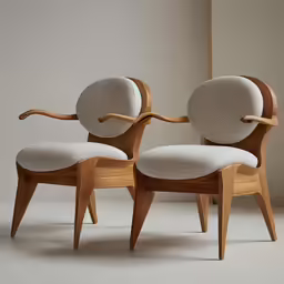 two wooden chairs sit side by side on the ground