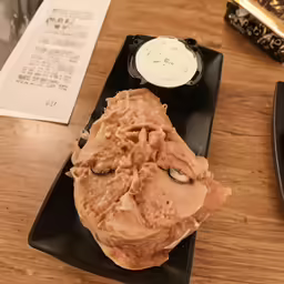 a table holding a black dish containing meat and cream