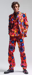 a man wearing an odd outfit, with an orange and blue pattern,a young man wearing brightly colored clothing and a black hat
