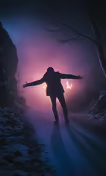 person with arms outstretched on a path in the dark