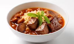 a white bowl of soup with meat, noodles and garnishes