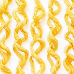 a group of wavy yellow pasta noodles arranged on a white background