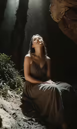 a beautiful woman sitting on the ground in a wooded area