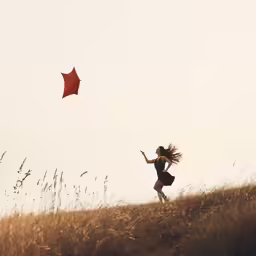 a woman flying a kite on top of a grass covered field
