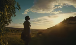 a person standing next to a tree during the sunset