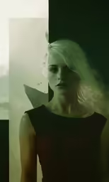 a woman with white hair and blue eyes stares into the camera