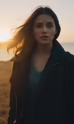 a young woman standing on top of a beach next to the ocean