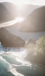 an ocean has the sun shining over rocks