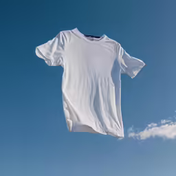 an unbuttoned white t shirt hangs out against a clear blue sky