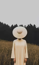 a woman with a hat on her head in a field