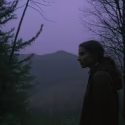 a young woman is standing alone in the woods