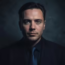 a man with a tie standing in front of a dark background