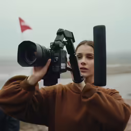 a young woman is holding a camera up to her face