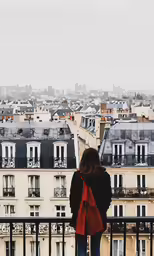 a woman standing on top of a balcony overlooking the city