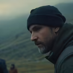 man looking at the camera with a green hill in the background