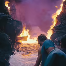 two people in the water watching a fire consume