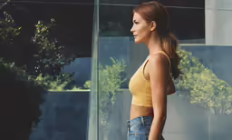 a young woman wearing short denim shorts and a yellow top, looking off to the side