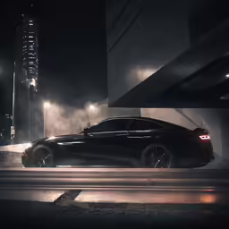 a black car driving past tall buildings at night