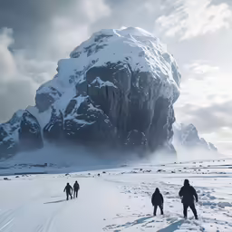 three people walk through the snow, with a huge rock in the background