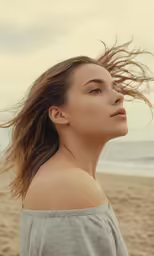 a woman on the beach with her hair blowing