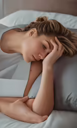 a beautiful woman laying on top of a bed