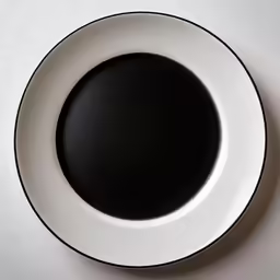 there is a black saucer on the white plate