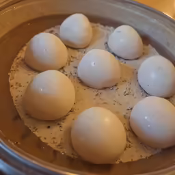 five raw eggs are laying in a silver bowl