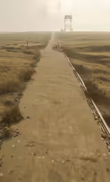 an empty paved road surrounded by brown grass