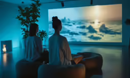 two women sitting in front of a screen on the wall