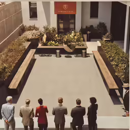 a group of people stand on a ledge looking at an outside garden