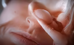 a baby girl is holding its nose to her breast