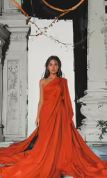 a woman in an orange dress posing for the camera