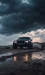 a black car driving in a wet road under a cloudy sky