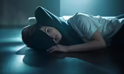 a girl lays on the floor with her hands behind her head and wears a blue mask