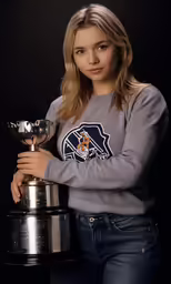 a beautiful woman holding a trophy while standing in front of a black background
