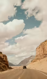 car riding on open road between two canyons