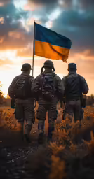 three soldiers in uniform carrying the ukraine flag