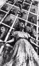 an old photo of a woman standing outside with pictures in front of her