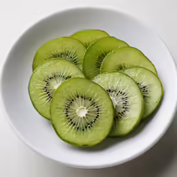 sliced kiwi in a white bowl with a spoon
