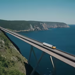 a train is traveling on an overpass that stretches into the water