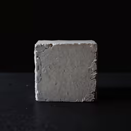 a block of white soap sitting on top of a black surface