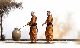 two men dressed in orange robes standing by a large ball and pole