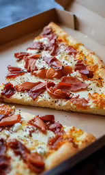 two slices of pizza with bacon sitting on top of cardboard boxes
