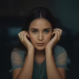 a woman in blue shirt and gray tee looking straight ahead