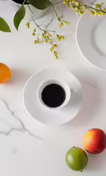 three small fruits are near a cup of coffee on a marble counter