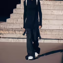 a woman with black hair is on the catwalk