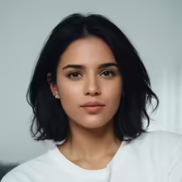 a woman with long black hair and white shirt looking into the camera